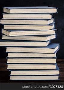 stack of books in a blue cover on a brown wooden table, close up