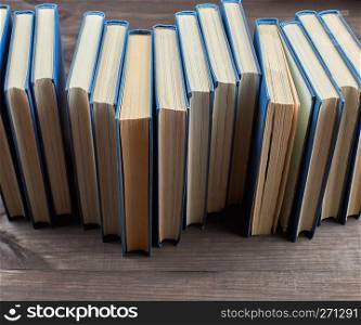 stack of books in a blue cover on a brown wooden table, top view
