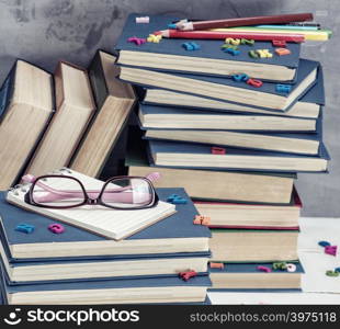 stack of books in a blue cover, pink glasses on top, close up