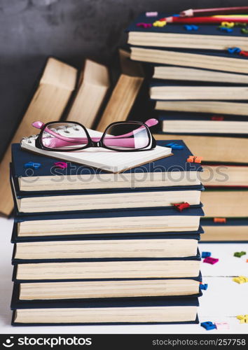 stack of books in a blue cover, pink glasses on top, vintage toning