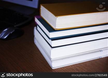 Stack of books near computer on desk