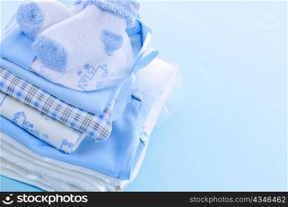 Stack of boy infant clothing for baby shower on blue background