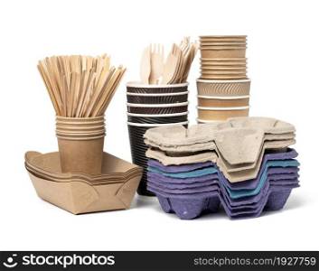 stack of brown disposable paper cups, wooden forks and knives, plate on a white background. Utensils for takeaway drinks, zero waste