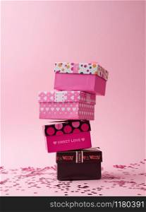stack of cardboard square gift boxes on a pink background with shiny confetti, festive backdrop