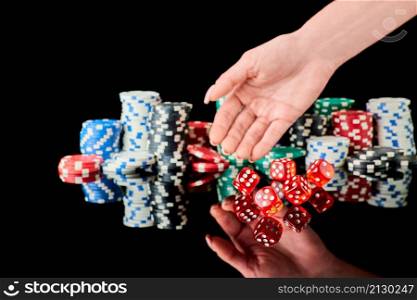 Stack of Casino gambling chips and red dices isolated on reflective black background.. Stack of Casino gambling chips and red dices isolated on reflective black background