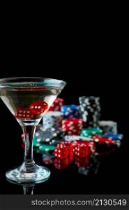 Stack of Casino gambling chips, glass of martini vermouth and red dices isolated on reflective black background.. Stack of Casino gambling chips, glass of martini vermouth and red dices isolated on reflective black background
