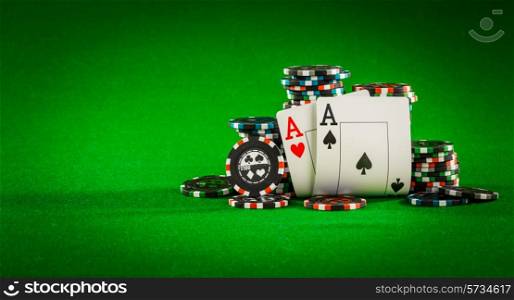 Stack of chips and two aces on the table on the green baize - poker game concept