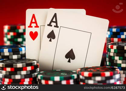 Stack of chips and two aces on the table on the red baize - poker game concept