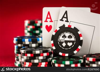 Stack of chips and two aces on the table on the red baize - poker game concept