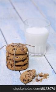 Stack of chocolate chip cookies with glass of fresh milk on blue wooden table