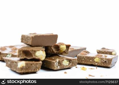 Stack of chocolate pieces with nuts in close-up and isolated on white background.
