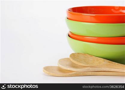 stack of clean empty plates and wooden spoons on white background