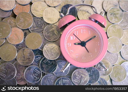 Stack of coins with pink fashioned alarm clock for display planning money financial and business accounting concept, time is money concept with clock and coins, time to work at make money, vintage color tone