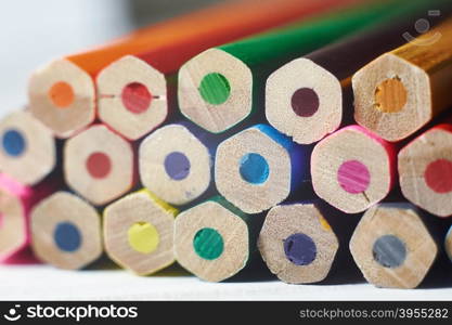 Stack of colored pencils on white table. Studio shot