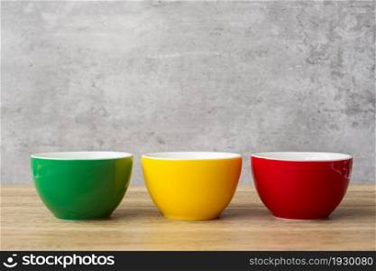 stack of colorful coffee cups on wall background at cafe. Green, yellow and red color ceramic mug on table at home. International coffee day concept