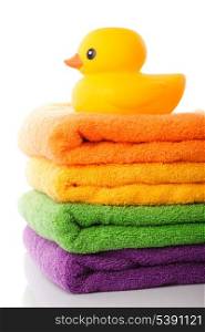 Stack of colorfull towels and yellow rubber duck isolated on white