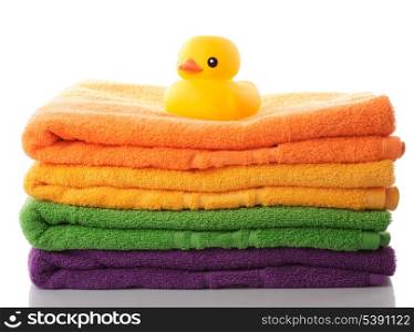 Stack of colorfull towels and yellow rubber duck isolated on white