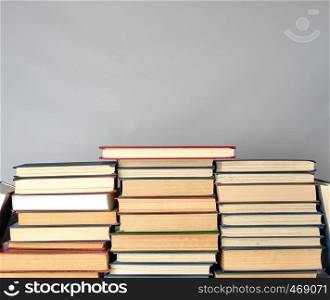 stack of different books on a gray background, copy space
