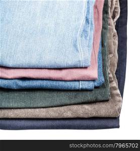 stack of different jeans and corduroys close up isolated on white background