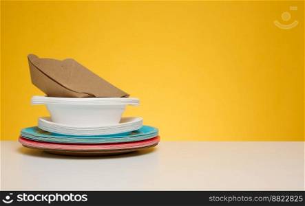 Stack of disposable paper plates on yellow background, copy space