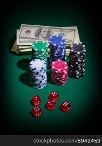 Stack of dollars dices and chips on green table
