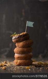 Stack of Donuts with crumbs, nuts and flag on dark stone background