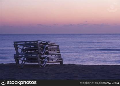 Stack of folded lounge chairs on the beach, South Beach, Miami, Florida, USA