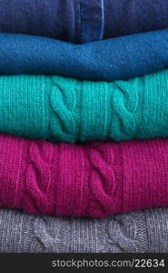 stack of folded woolen gray, green, blue and red clothes background