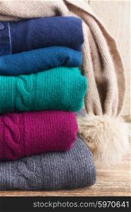 stack of folded woolen gray, green, blue and red clothes close up