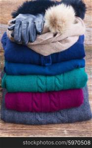stack of folded woolen gray, green, blue and red clothes with gloves close up