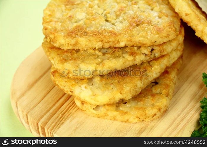 Stack of fried hash browns on a board ready to serve.