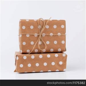 stack of gifts in boxes wrapped in brown kraft paper and tied with rope on a white background. Festive concept, copy space