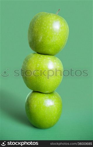 Stack of green apples over colored background