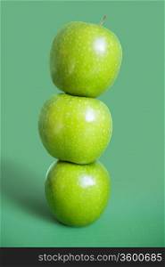 Stack of green apples over colored background