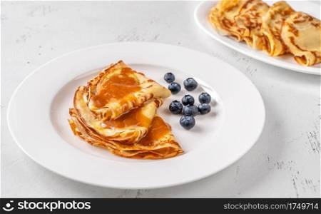 Stack of homemade crepes topped with caramel and fresh blueberries