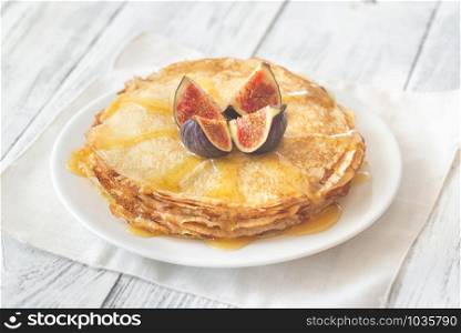 Stack of homemade crepes with fresh fig and sweet topping on the white plate