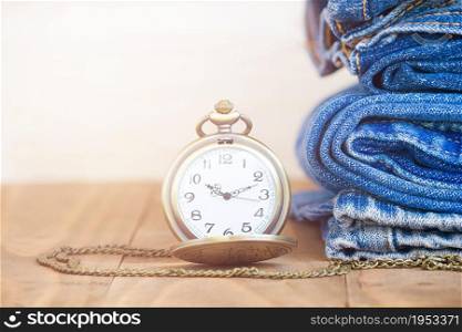 Stack Of Jeans And Classic Timepieces On Old Wood Flooring,Fashion Concept With Time
