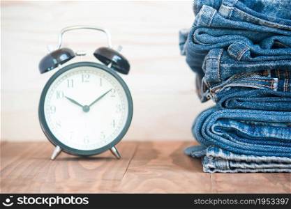Stack Of Jeans And Classic Timepieces On Old Wood Flooring,Fashion Concept With Time