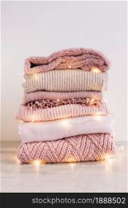 stack of knitted sweaters with garland on floor. Resolution and high quality beautiful photo. stack of knitted sweaters with garland on floor. High quality and resolution beautiful photo concept