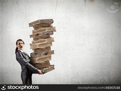Stack of knowledge. Young businesswoman carrying pile of old books