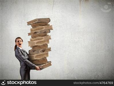 Stack of knowledge. Young businesswoman carrying pile of old books
