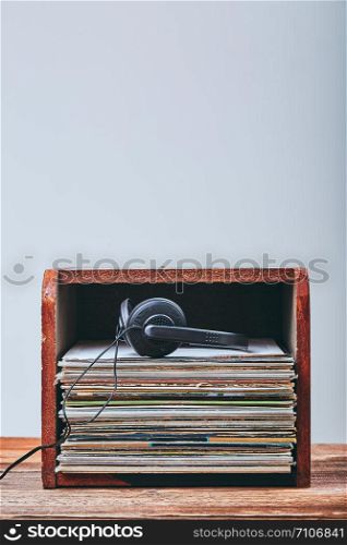 Stack of many black vinyl records and headphones put on the top of stack. Candid people, real moments, authentic situations