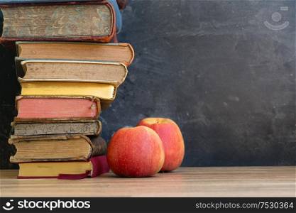 Stack of multicolored books with two apples, education, reading, back to school concept, copy space. Pile of old books