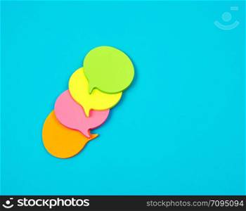 stack of multicolored empty paper stickers in the form of clouds on a blue background, copy space