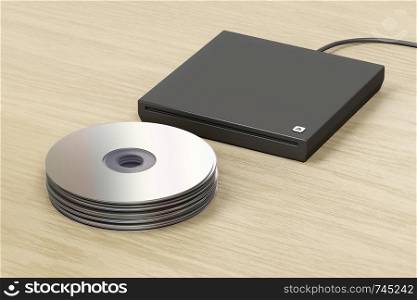 Stack of optical discs and external slot-loading optical drive on wood table