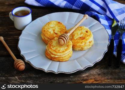 Stack of pancakes with honey syrup on wooden dark background.