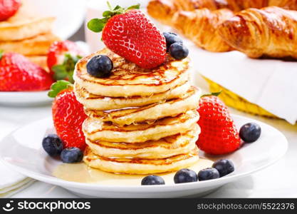 stack of pancakes with syrup, strawberry and blueberry