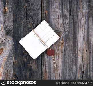 stack of paper cards tied with a rope with a stamp on a gray old wooden background, top view