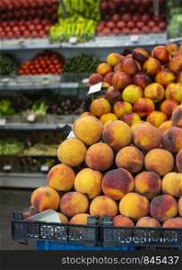 Stack of peaches in the market. Shelf with fruits on the background.