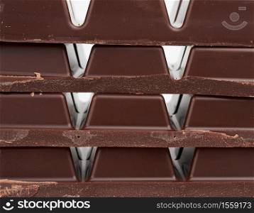 stack of pieces of black chocolate on a white background, delicious dessert and ingredient for cooking, close up